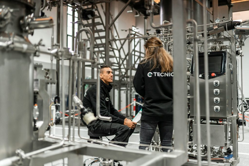 Two technicians discuss factory equipment.