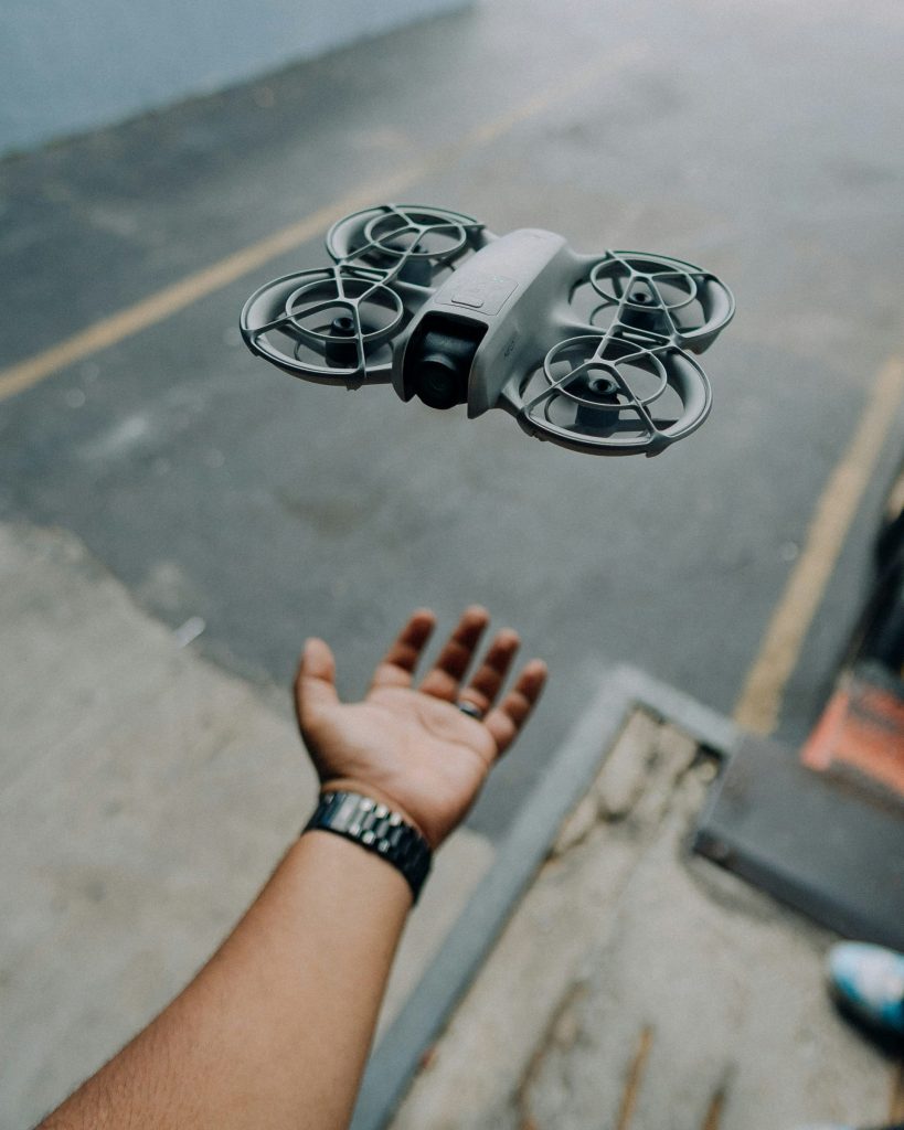 A drone hovers above a person's outstretched hand.